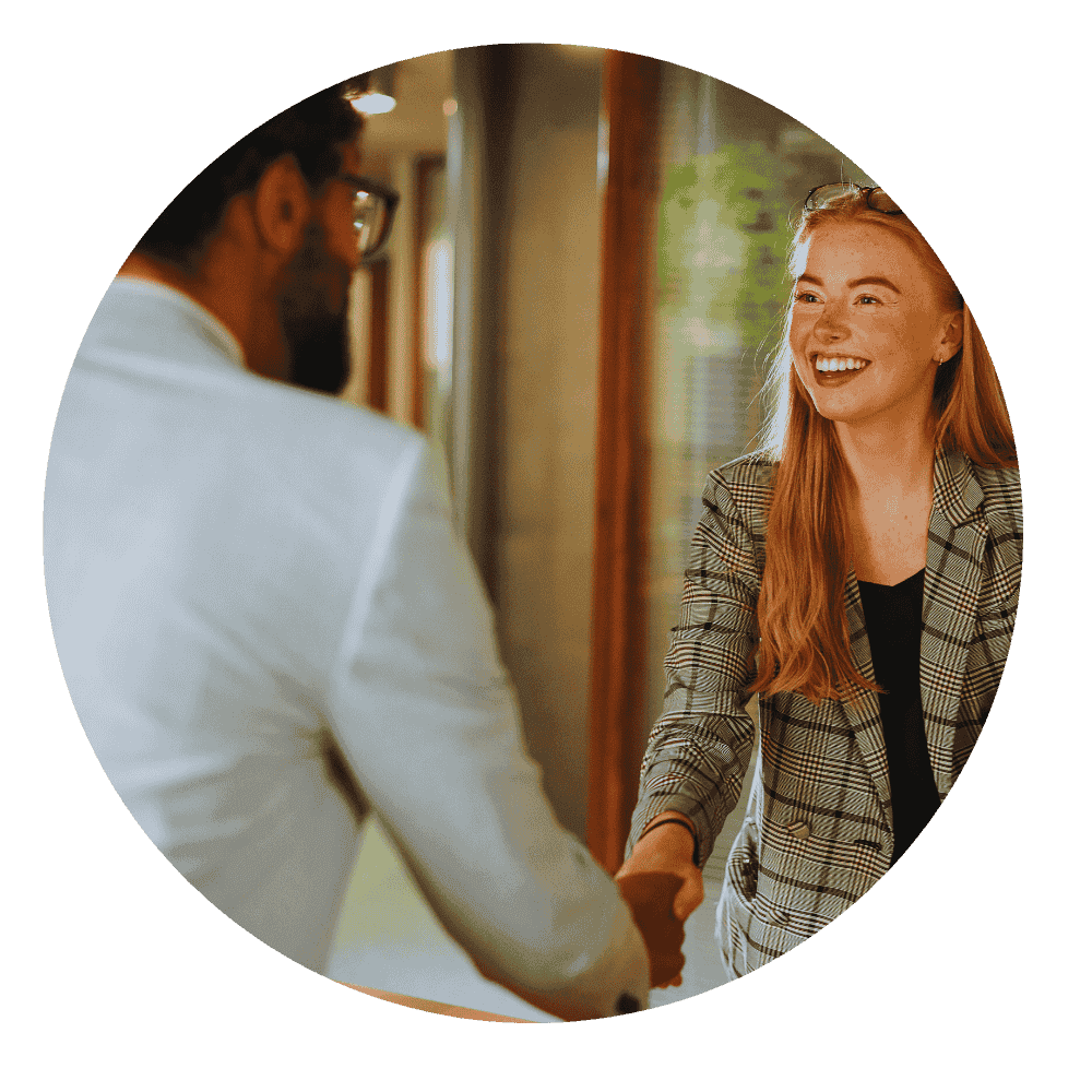 "Smiling female real estate agent shaking hands with a male client inside an office, symbolizing trust and professional agreement.