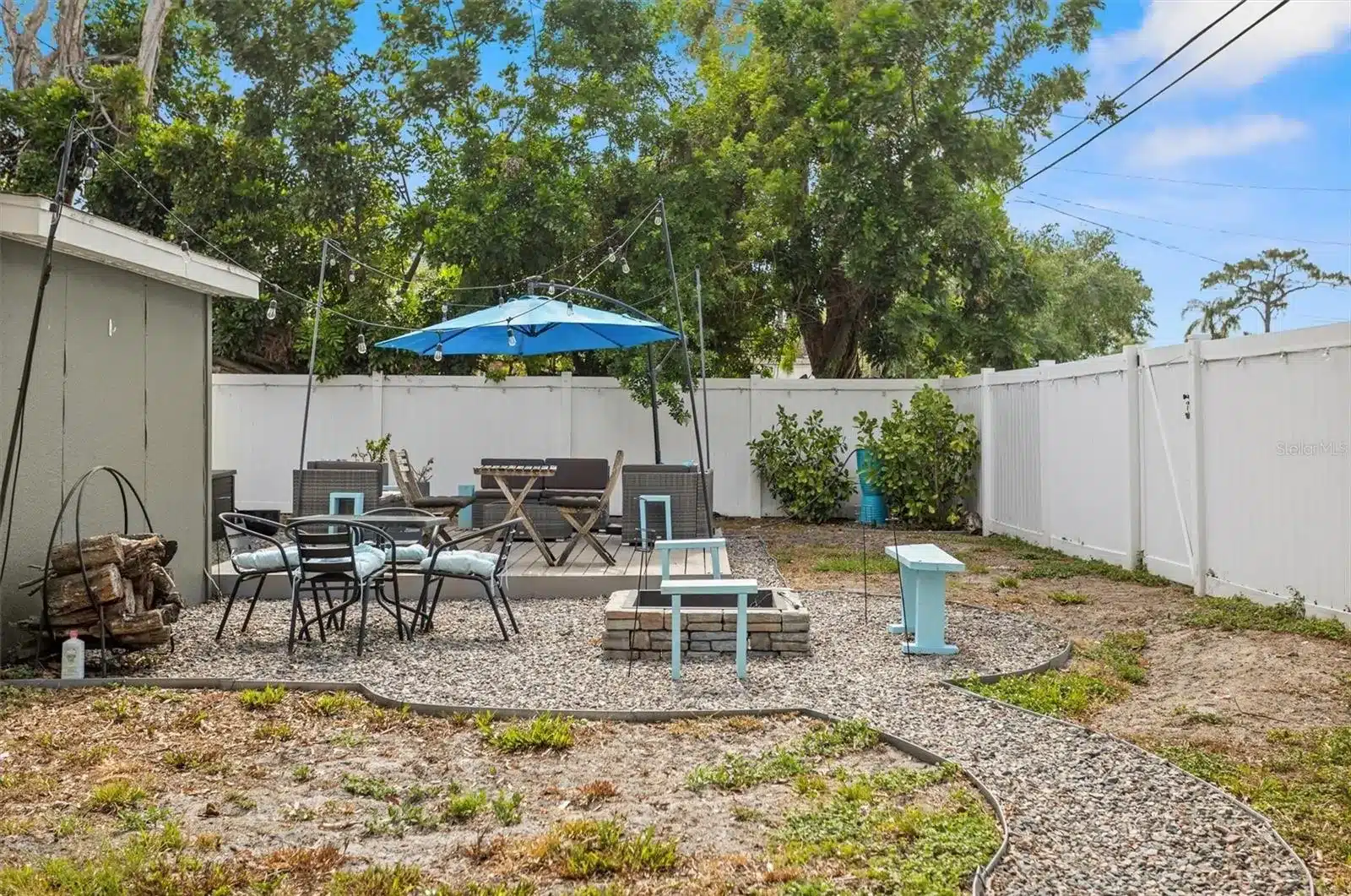 Outdoor patio with furniture, firepit, and string lights.