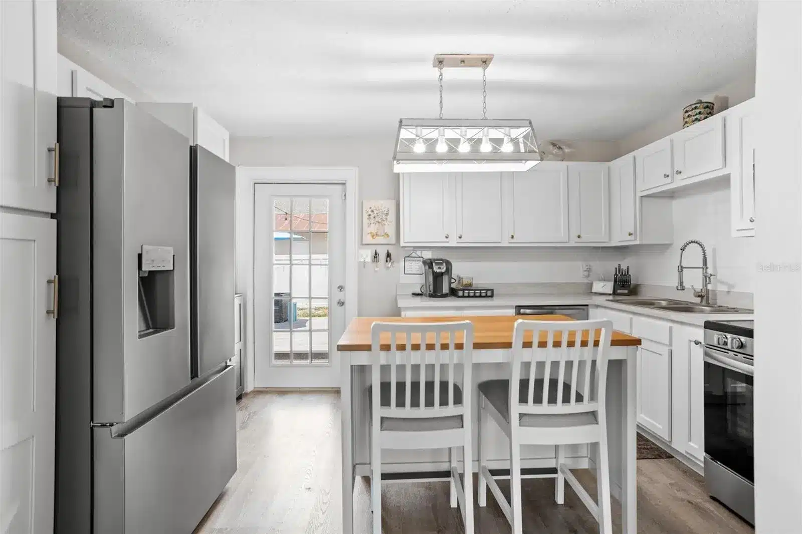 Modern kitchen with white cabinets and island seating.
