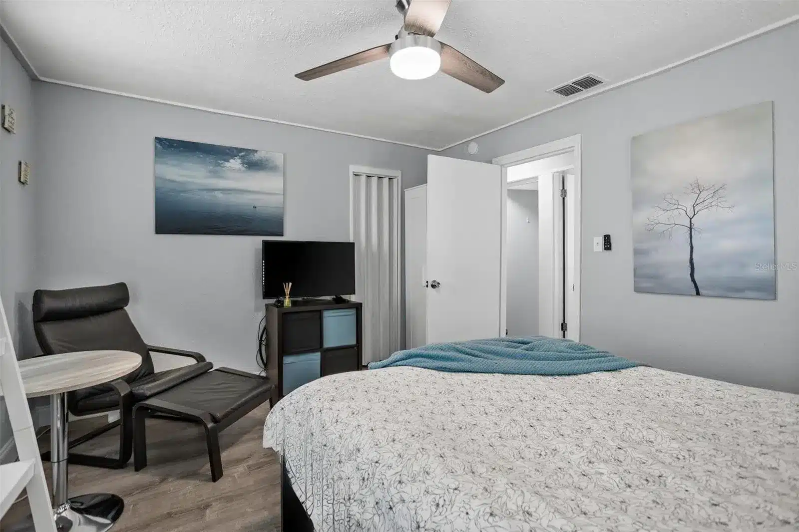 Bedroom with bed, chair, TV, and ceiling fan.