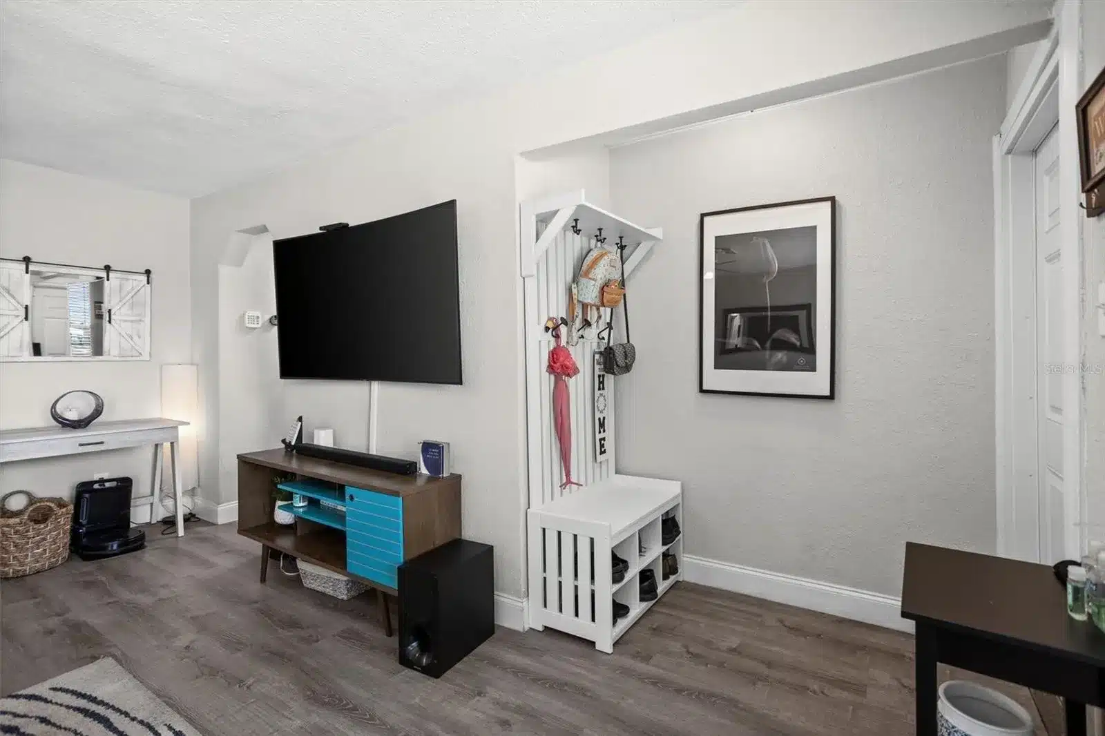 Living room with TV, coat rack, and white furniture.