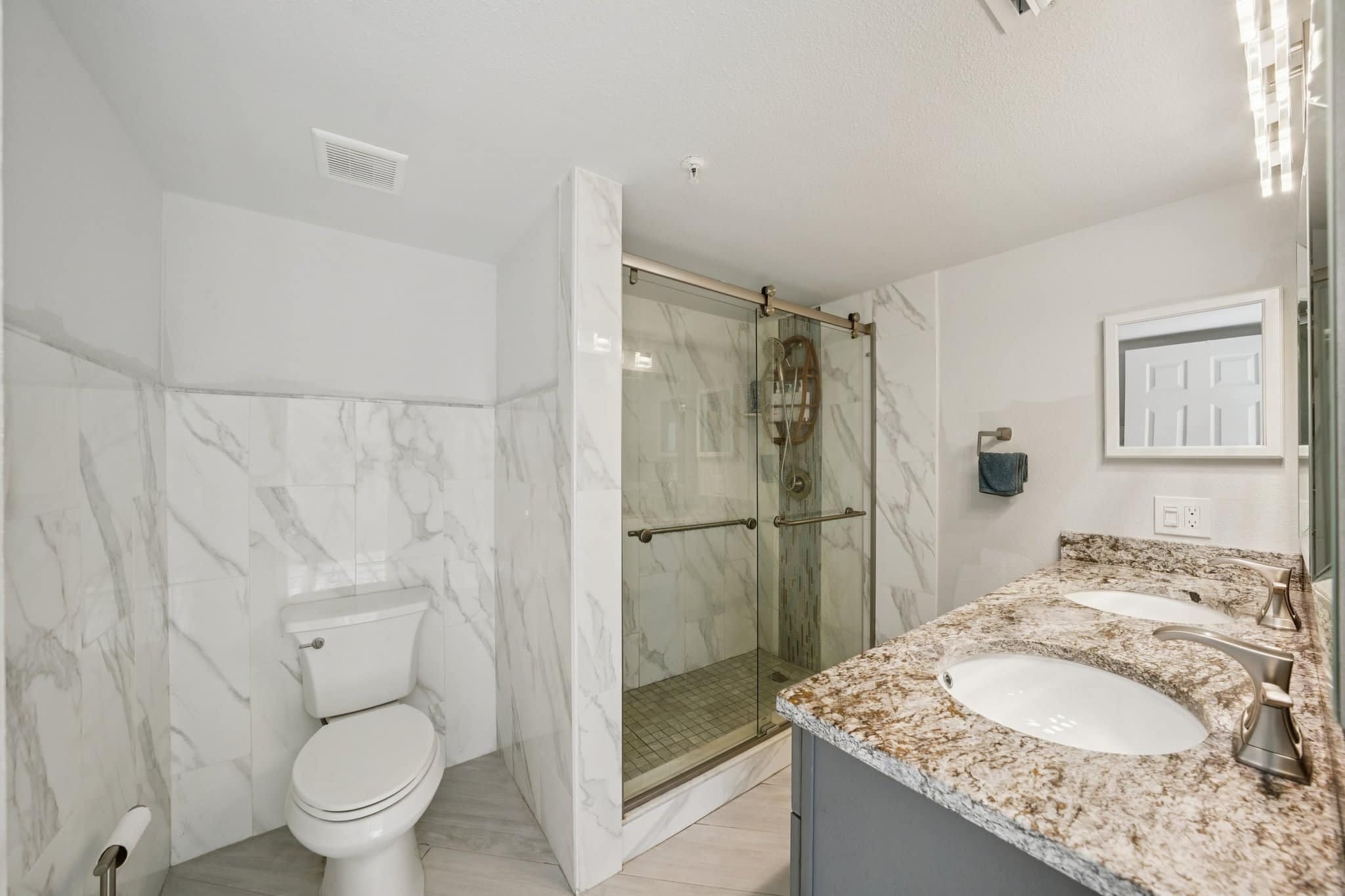 Modern condo bathroom with glass shower and dual sink vanity at 15316 Gulf Blvd Madeira Beach FL