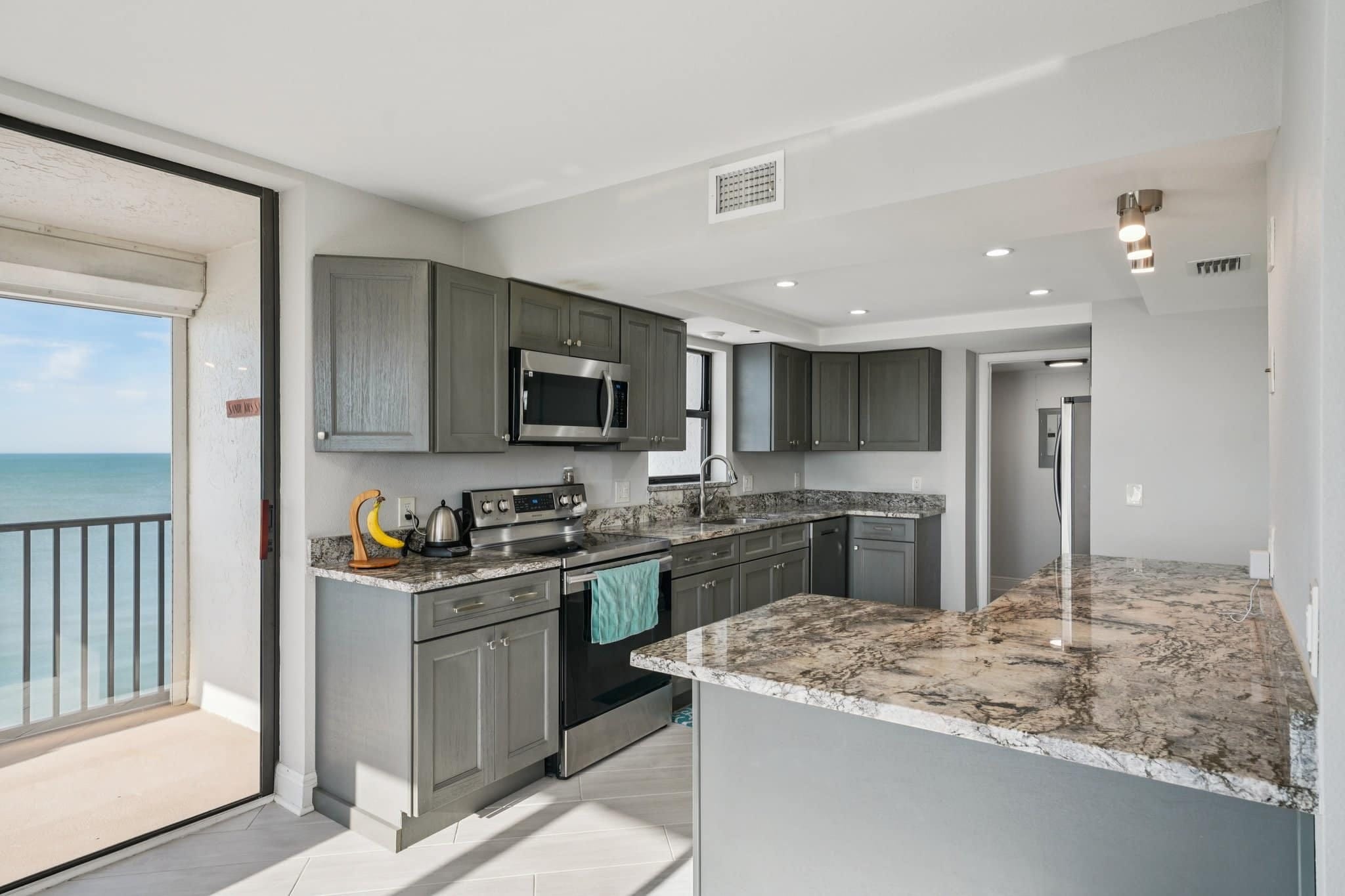 Modern condo kitchen with granite countertops and stainless steel appliances with Gulf view balcony at 15316 Gulf Blvd Madeira Beach FL