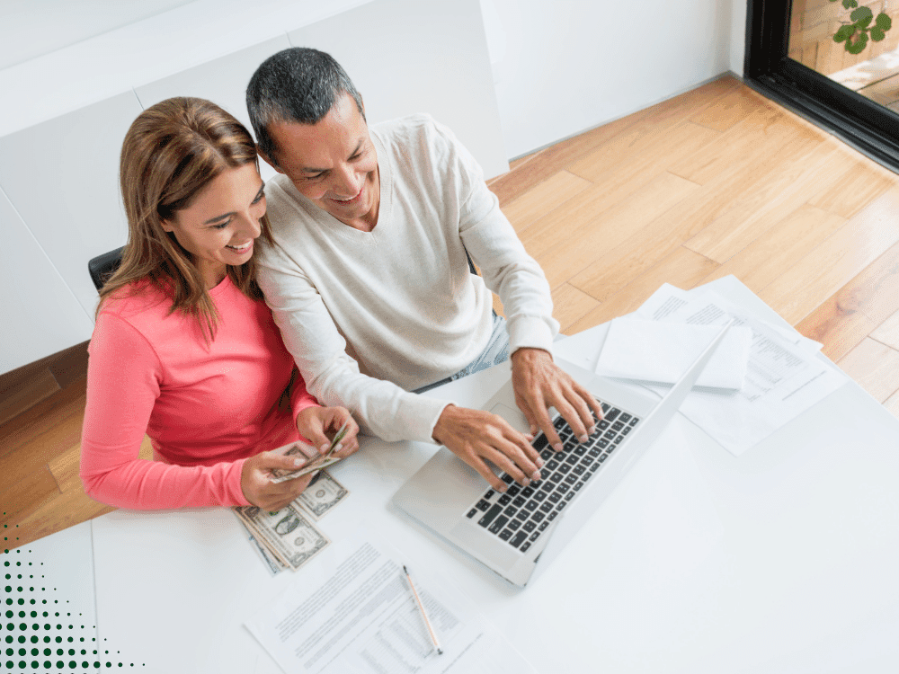 Couple reviewing financial documents and using a laptop together while managing home purchase finances.